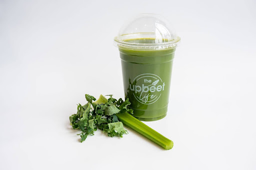 Bottle of smoothie with fresh cucumber and celery laid out next to it.